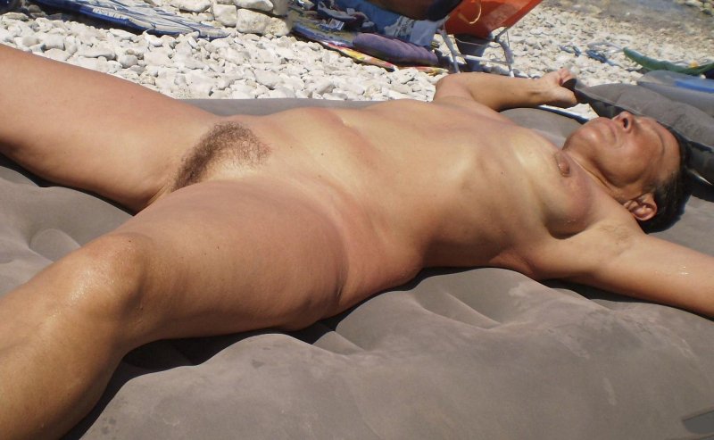 Загорает на пляже голой животе