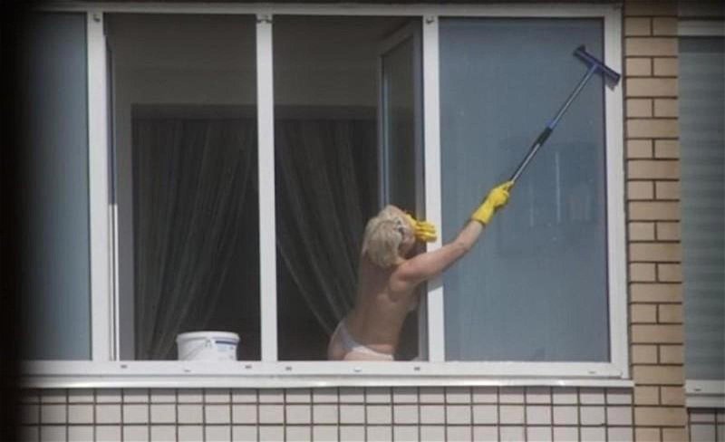 Женщина моет окно